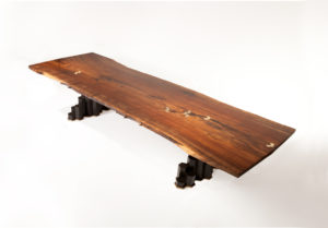 Handmade Filip dining table crafted from California walnut w/ hand-carved basalt base and bronze inlay